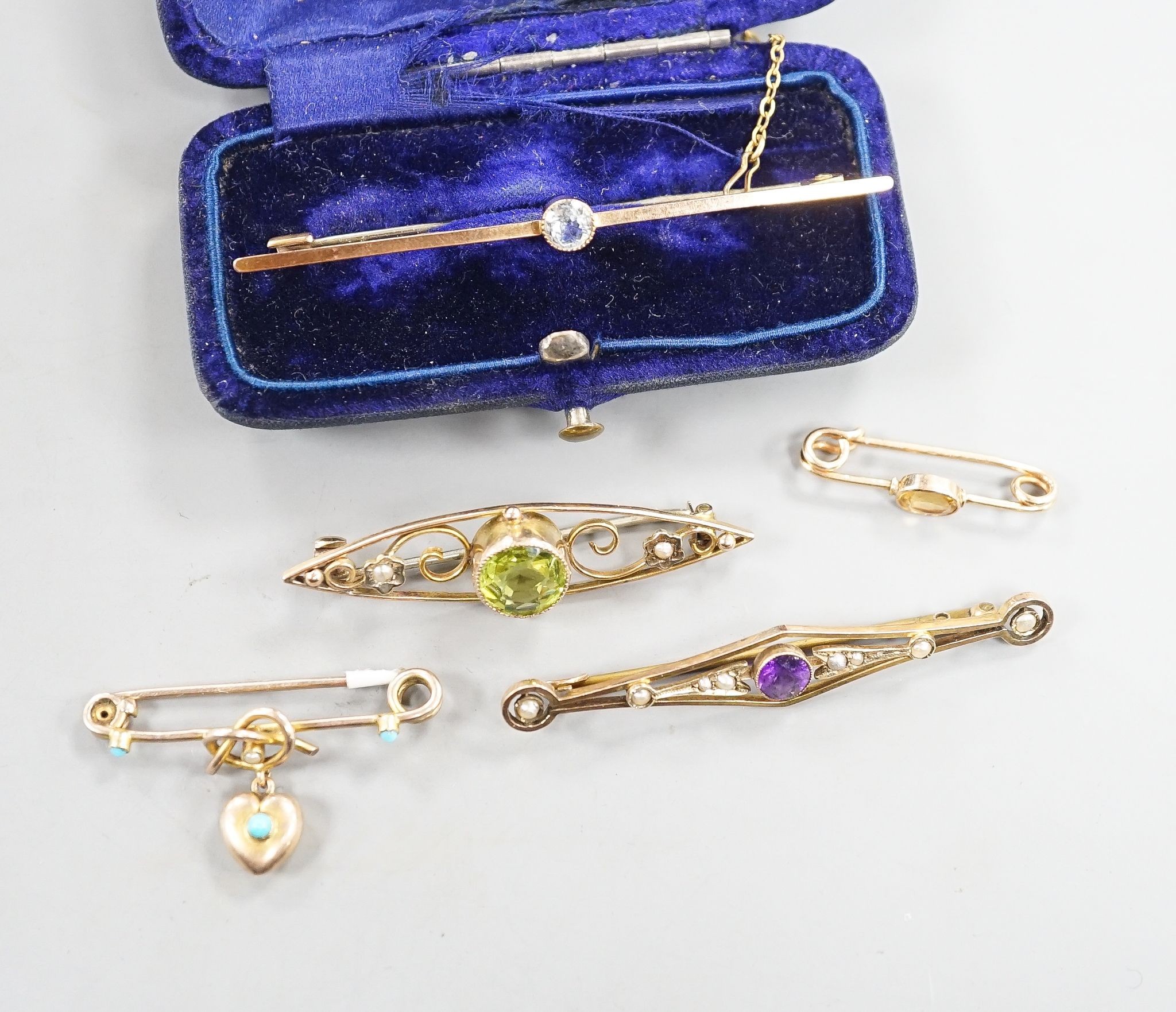 Five assorted early 20th century yellow metal and gem set brooches, including one 9ct and one with turquoise set heart drop and one with peridot, largest 62mm, gross 11.7 grams.